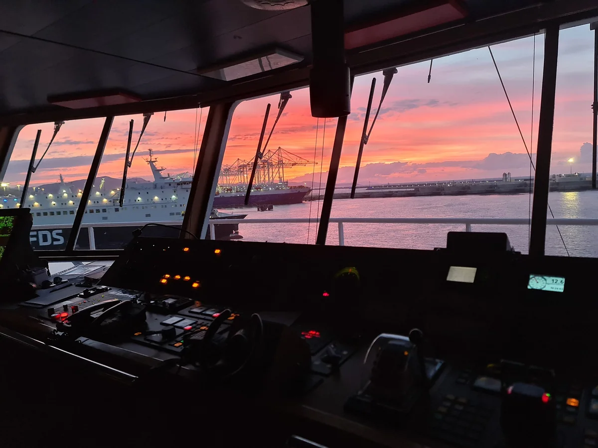 Navigation bridge during a maritime operation at sunset